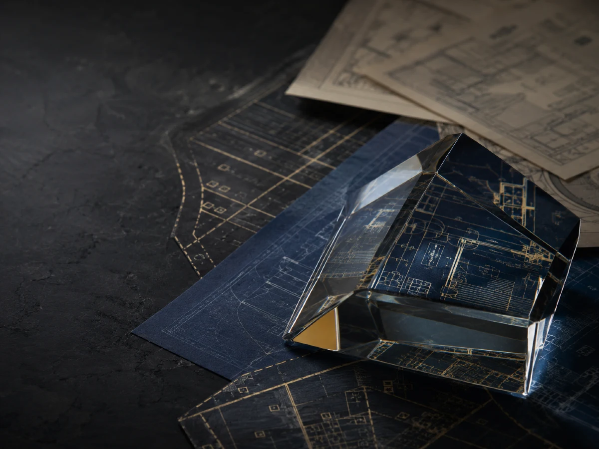 Architectural glass prism over building blueprints, supporting technology and privacy in real estate and property in Thailand